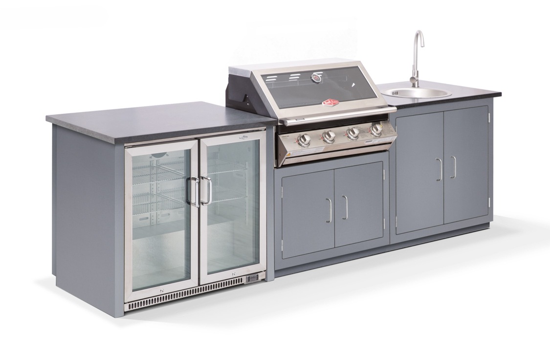 Grillstation mit Kühlschrank und Spüle, der Grill hat drei Knöpfe, der Kühlschrank hat zwei Glastüren, alles in grauen Schränken eingebaut, auf hellem Hintergrund.