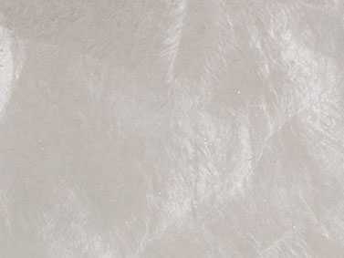 Eine weiße, strukturierte Oberfläche reflektiert leicht das Licht, ähnelt gefalteter Seide oder Pergamentpapier, ohne erkennbare Muster oder Text. Umgebende Details fehlen.