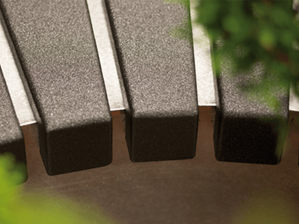 Gears depicted in a tight focus, resting in an industrial context, surrounded by blurred green foliage in the foreground, create a contrast between technology and nature.