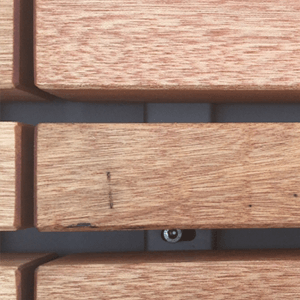 Holzbretter verlaufen horizontal, mit kleinen Lücken dazwischen. Eine Schraube ist durch eine der Lücken sichtbar. Die Oberfläche der Bretter ist glatt und hellbraun.