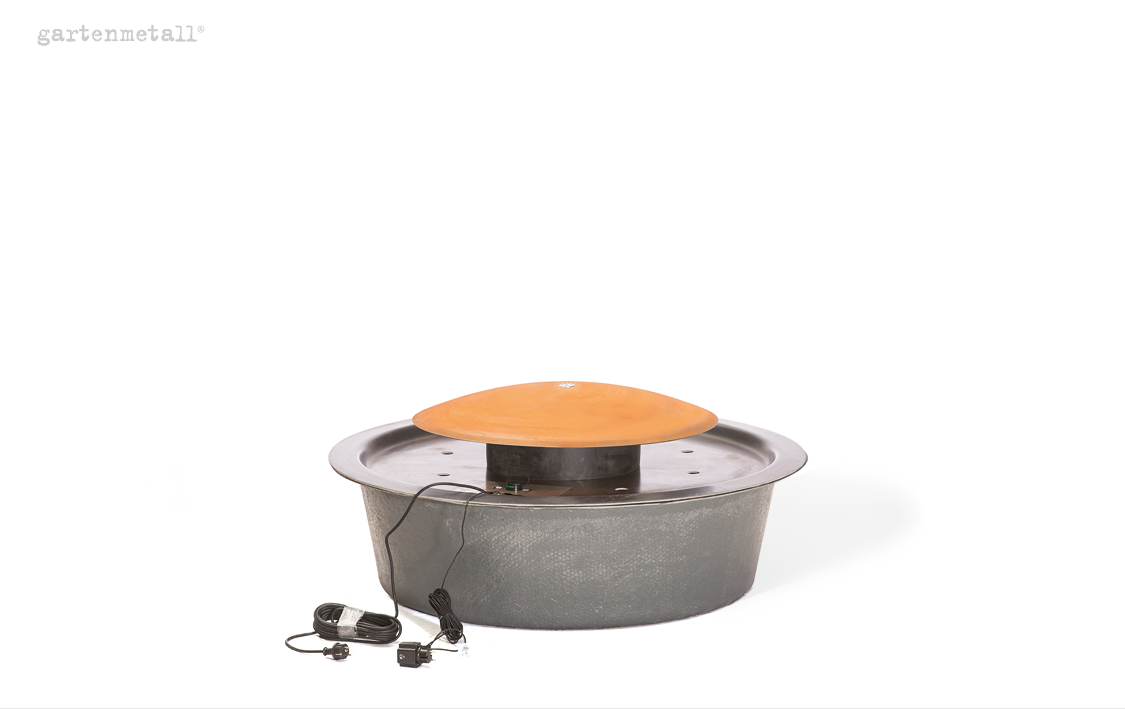 Runder Metallbrunnen mit Kupferdeckel, steht still. Kabel und Stecker liegen daneben. Hintergrund neutral weiß. Text: 'gartenmetall®'.
