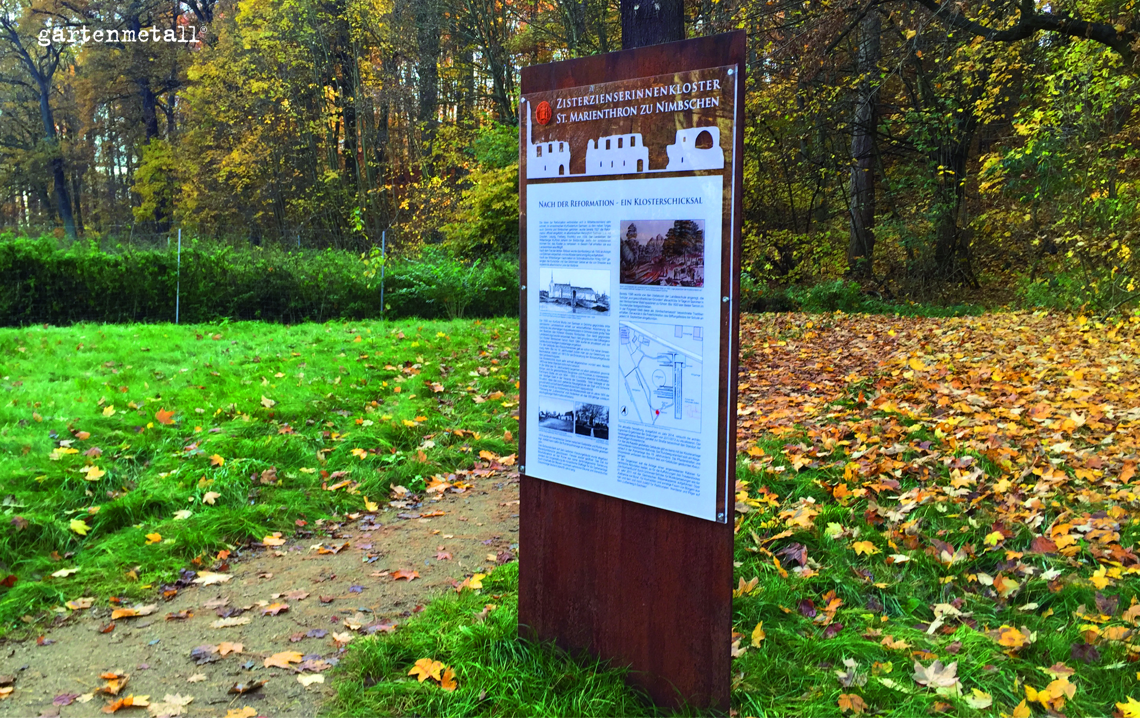 Schild zeigt Informationen über das 'Zisterzienserinnenkloster St. Marienthron zu Nimbschen' im herbstlichen Wald. Text: 'Nach der Reformation - Ein Klosterschicksal'. Umgebung voller Laubblätter.