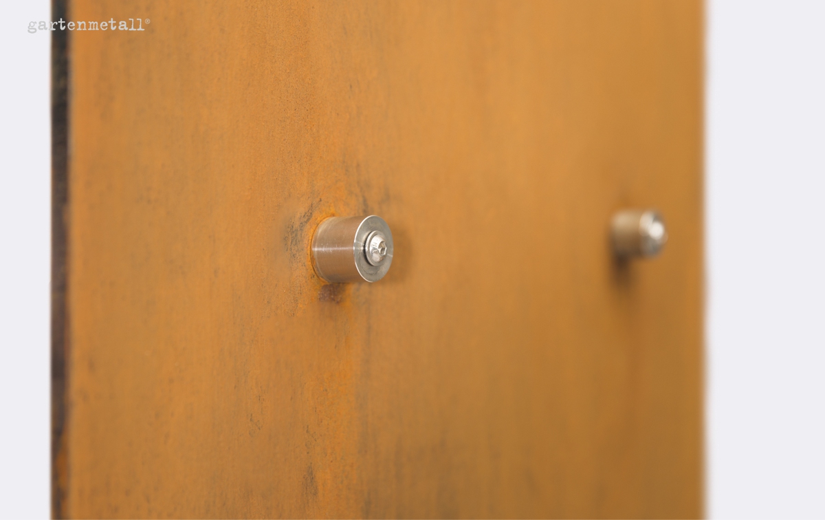 Metallischer Zylinderknopf ragt aus rostfarbener Metallplatte, umgeben von diffusem, hellem Hintergrund. Oben links steht Text: 'gartenmetall®'.
