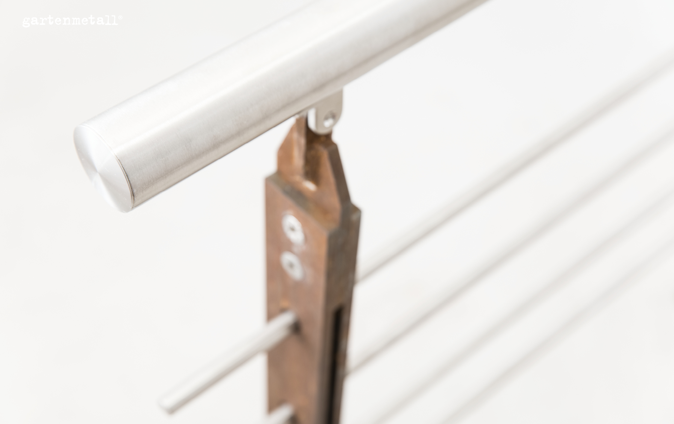 Handlauf, befestigt an Metallpfosten, in modernem, minimalistischem Design. Umgebung ist hell und unscharf. Text im Bild: 'gartenmetall®'.